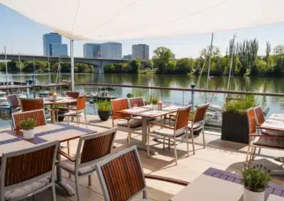 Sonnige Restaurantterrasse am Wasser mit Blick auf den Yachthafen und moderne Skyline