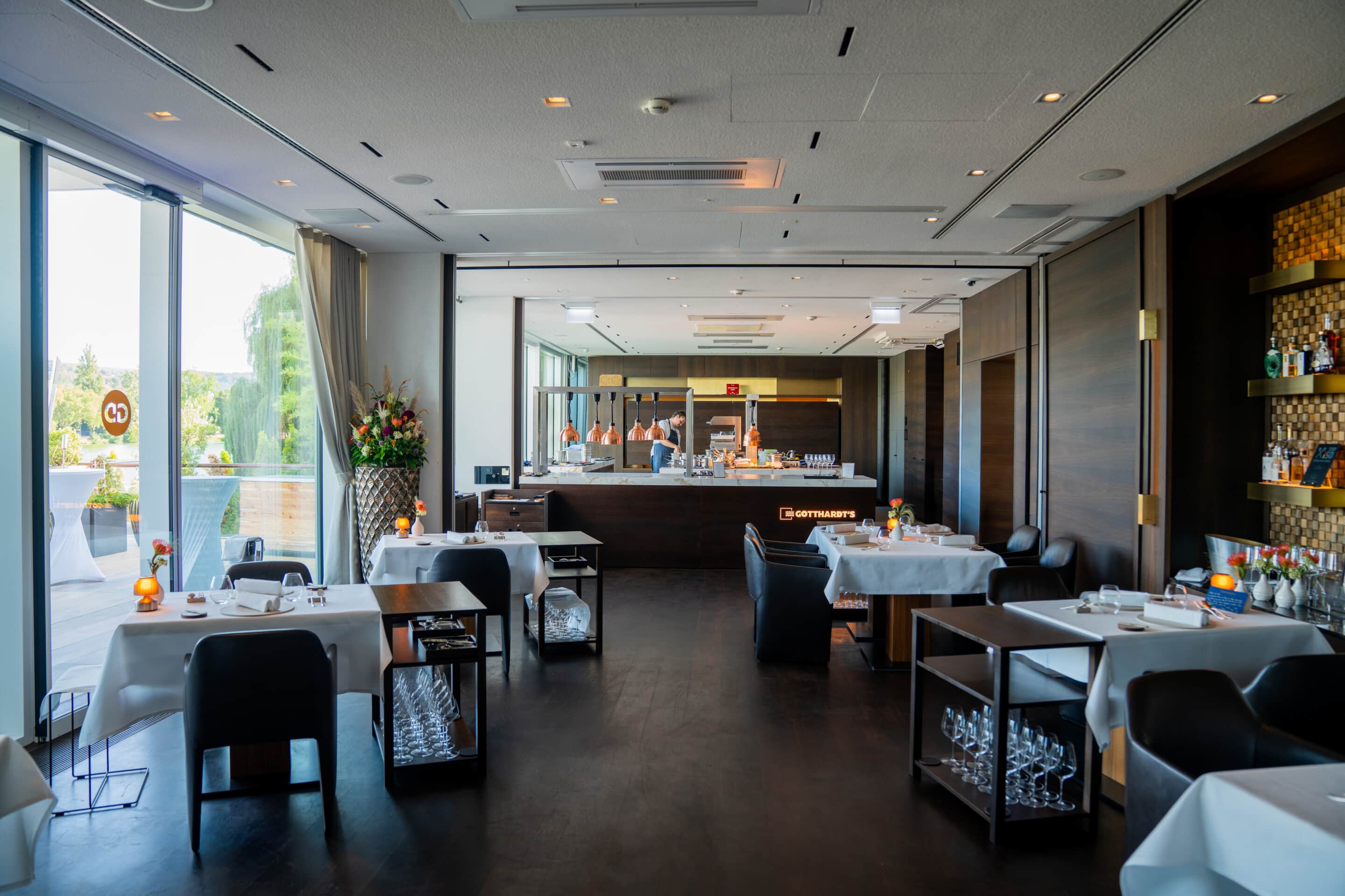 Innenbereich des Restaurants GOTTHARDT’S im FÄHRHAUS Koblenz mit gedeckten Tischen und offener Küche